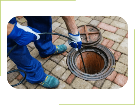 A person is using an air hose to loosen grease inside of a grease trap.