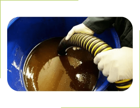 A person collecting used fryer oil from a restaurant with a vacuum hose.
